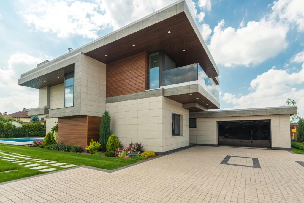 pexels-photo-8134847-8134847 Contemporary luxury house with a sleek design, lush garden, and blue sky.